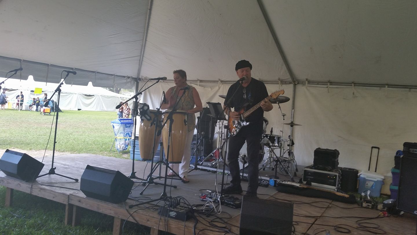 Musicians performing live on stage at outdoor event.
